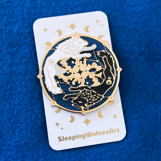 Decorative pin with gold and black design on a white card with 'SleepingWolvesArt' branding, against a blue textured background.
